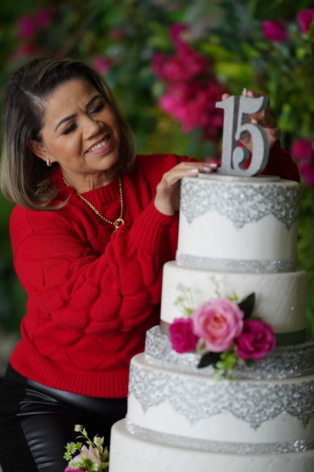 Eliane Cagé de blusa vermelha ao lado de um bolo cenográfico para festa de 15 anos